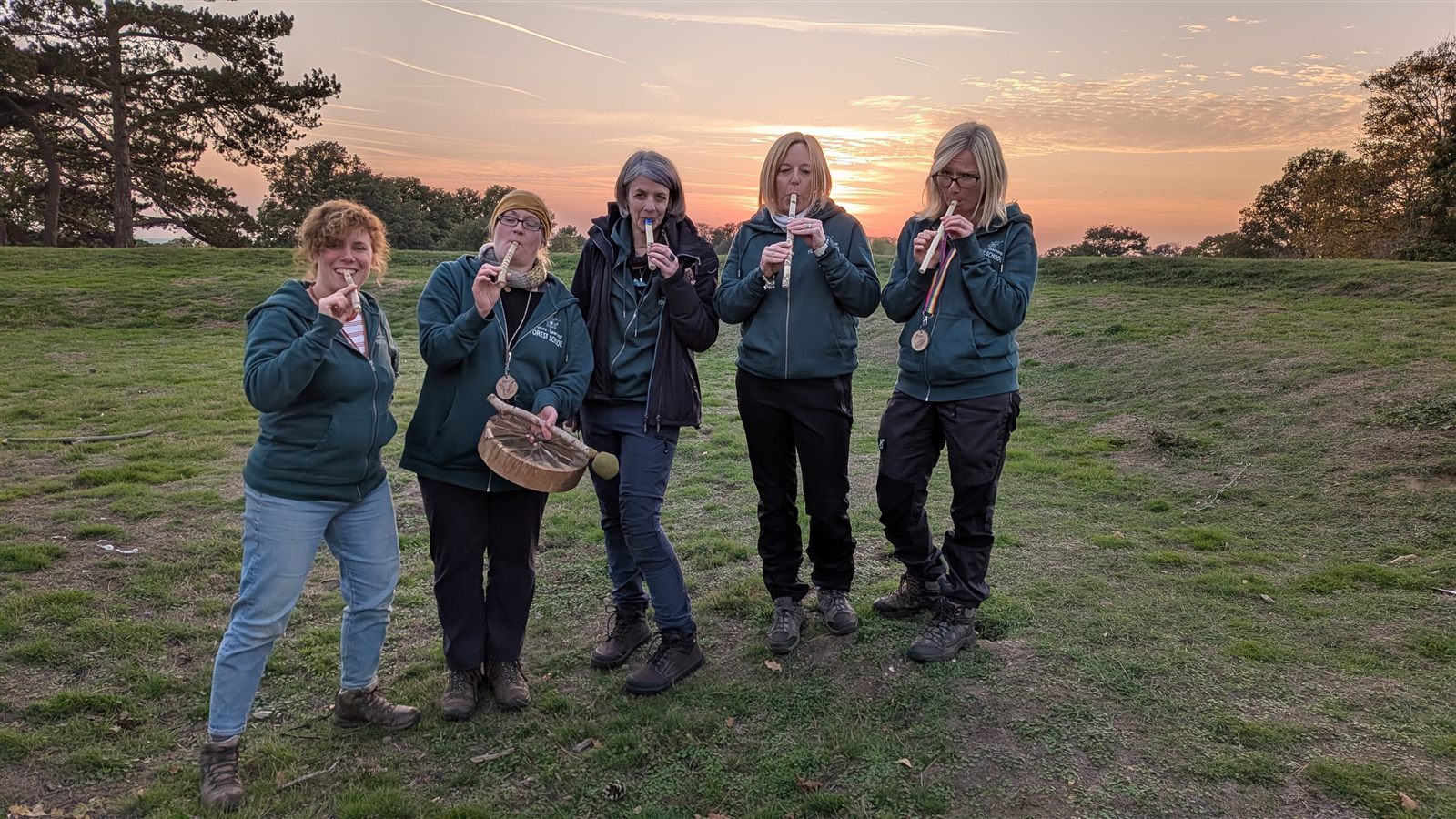 The Nature of Learning team of Forest School leaders in the woodland at sunset