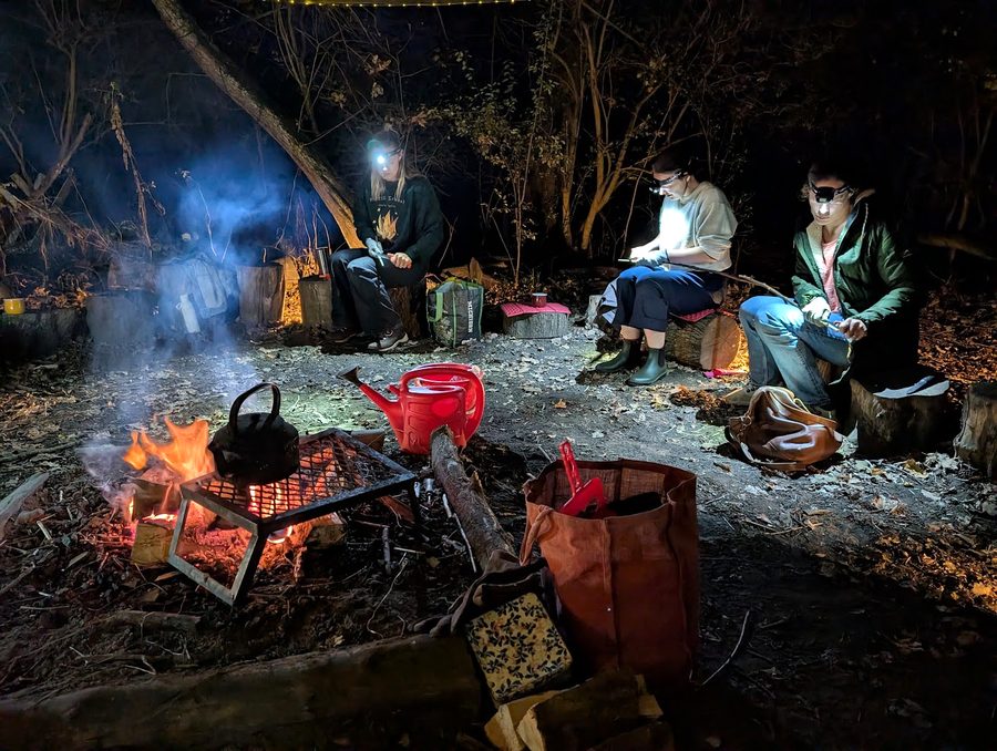 Whittling toasting sticks by head torch beside the fire