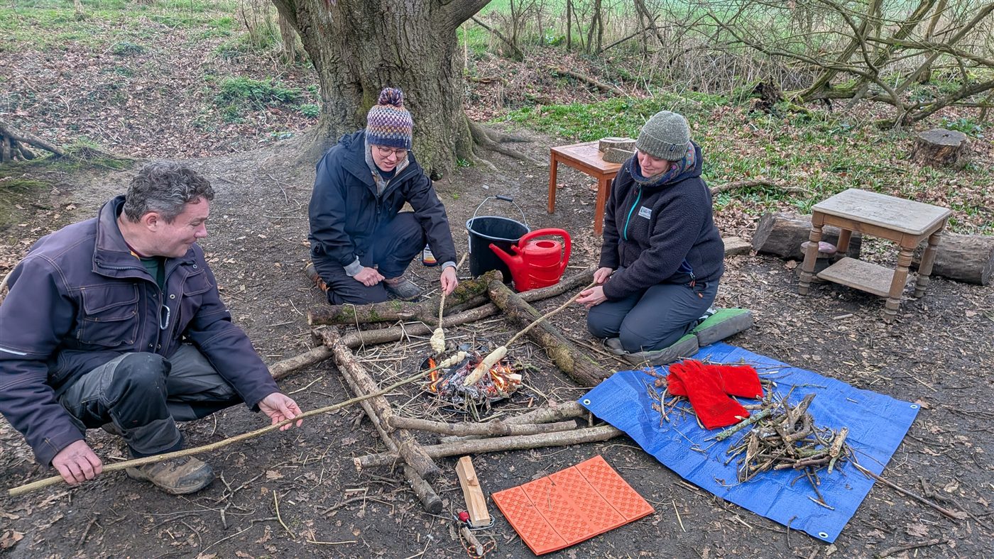 Trainees gathered around a small fire setup learning practical fire skills