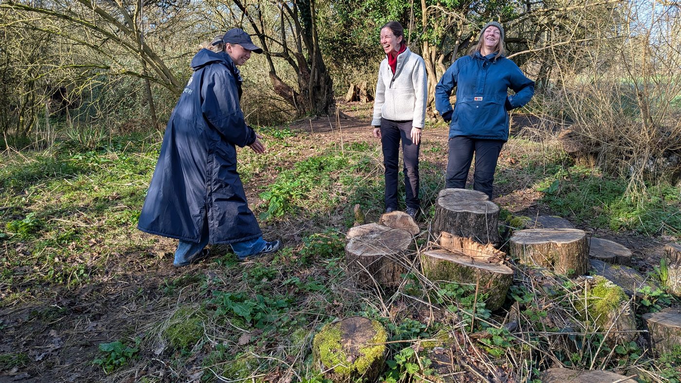 Trainees chatting around log seats in the sunny woodland
