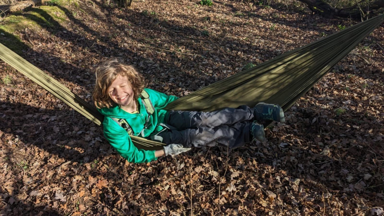 A child relaxing in a hammock among the autumn leaves at our woodland site