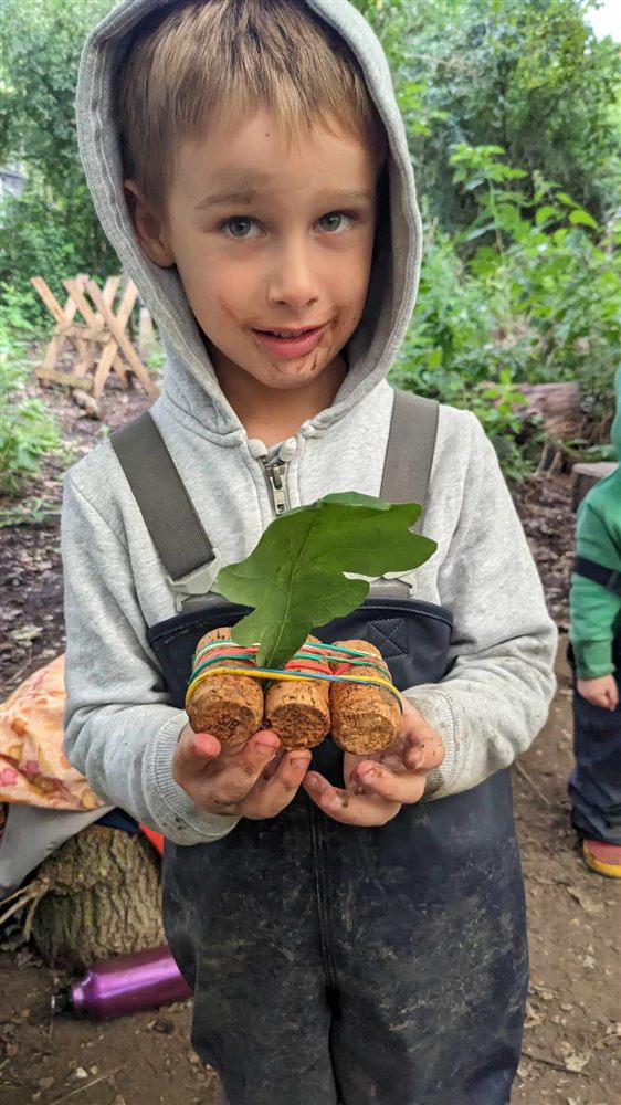 A child holding a cork raft with a leaf sail