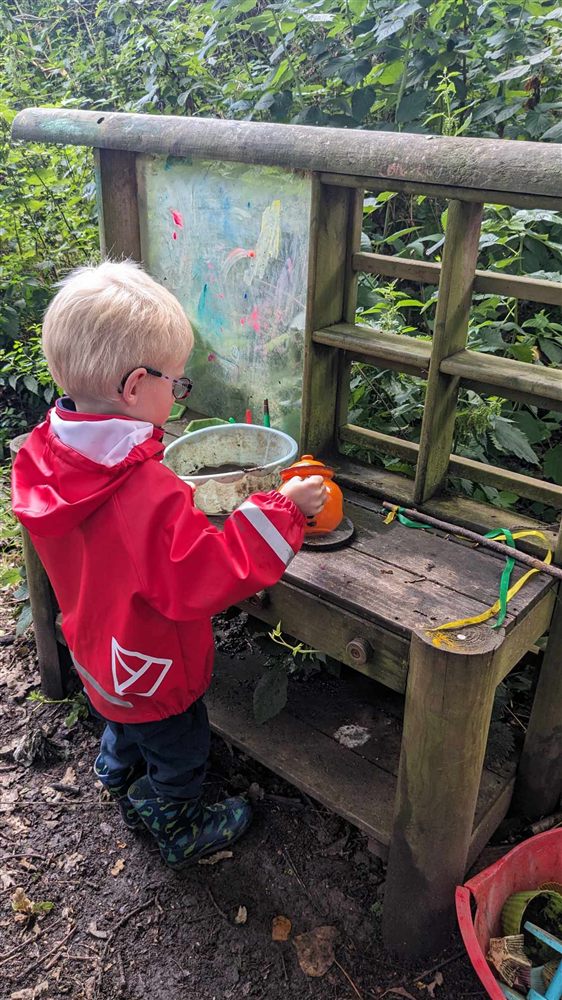 A toddler playing at the woodland mud kitchen